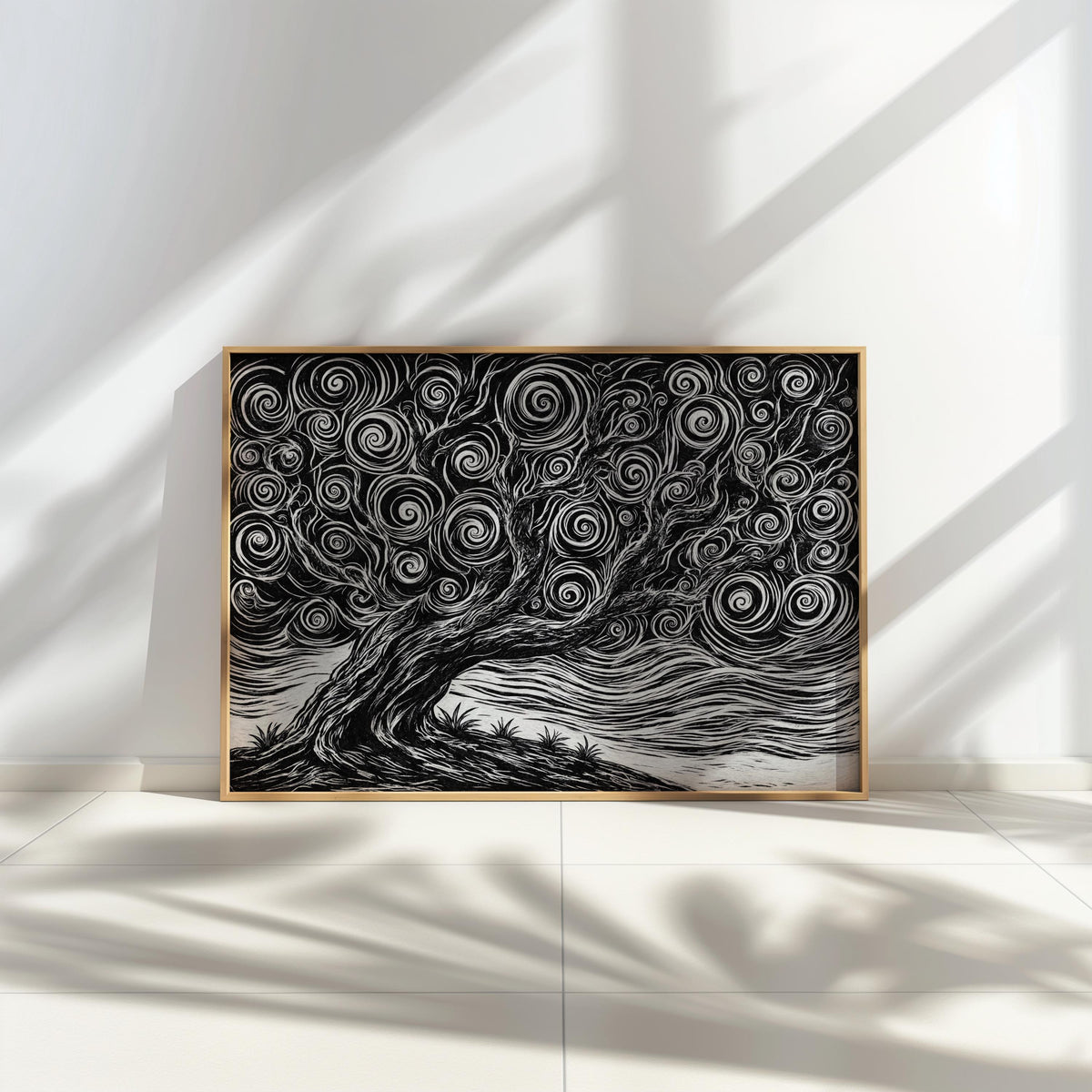 Framed black and white tree linocut print leaning against a sunlit wall, strong contrast and swirling wind lines visible