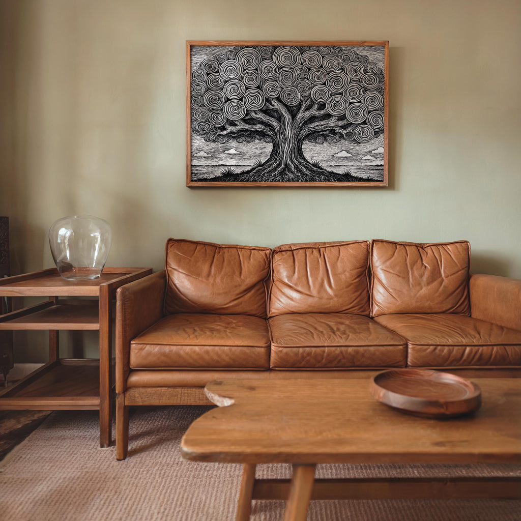 Black and white tree of life wall art, modestly sized above a brown leather sofa, boho living room with wood accents.