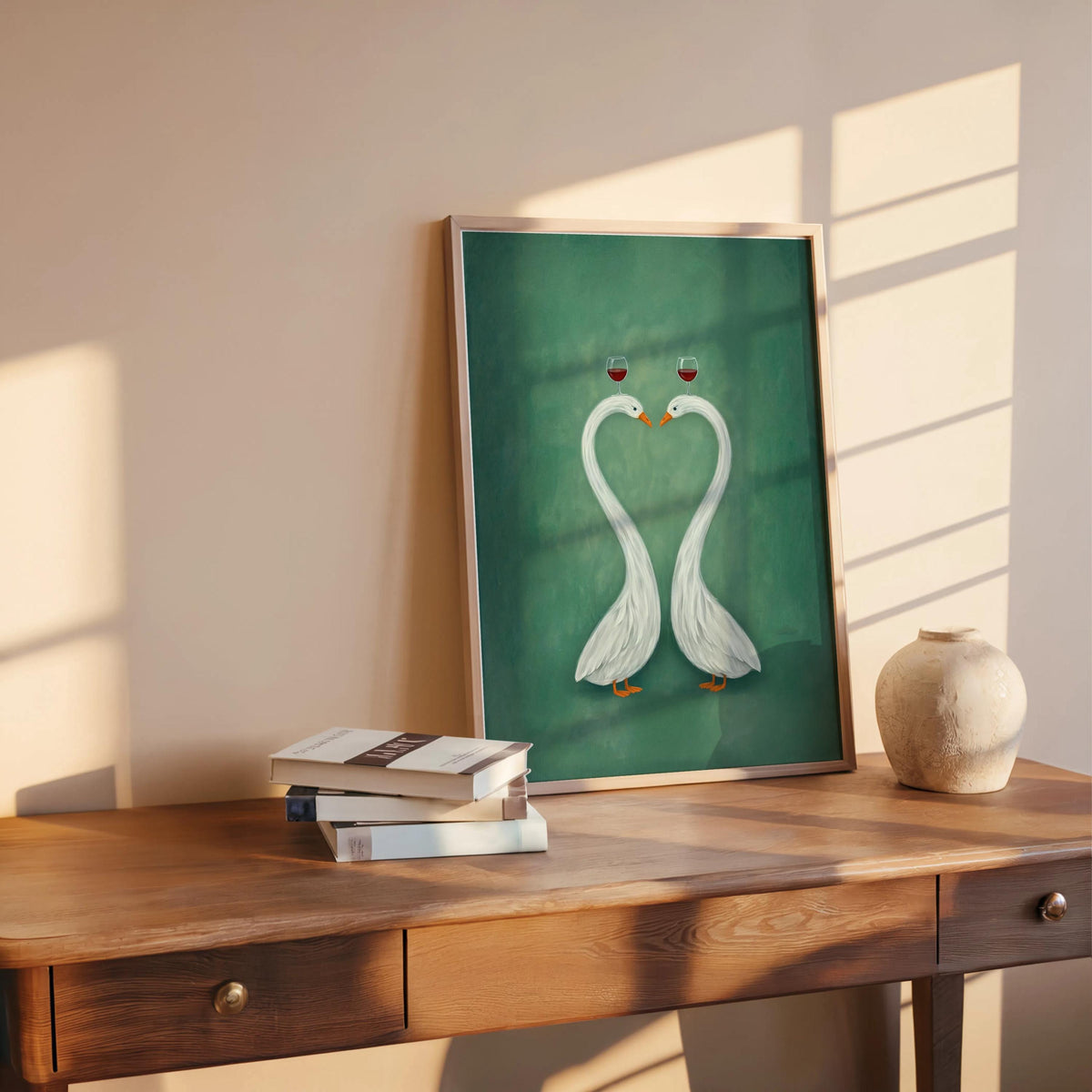 Green swan couple art print displayed on wooden table beside books and a vase, framed romantic swan wall art