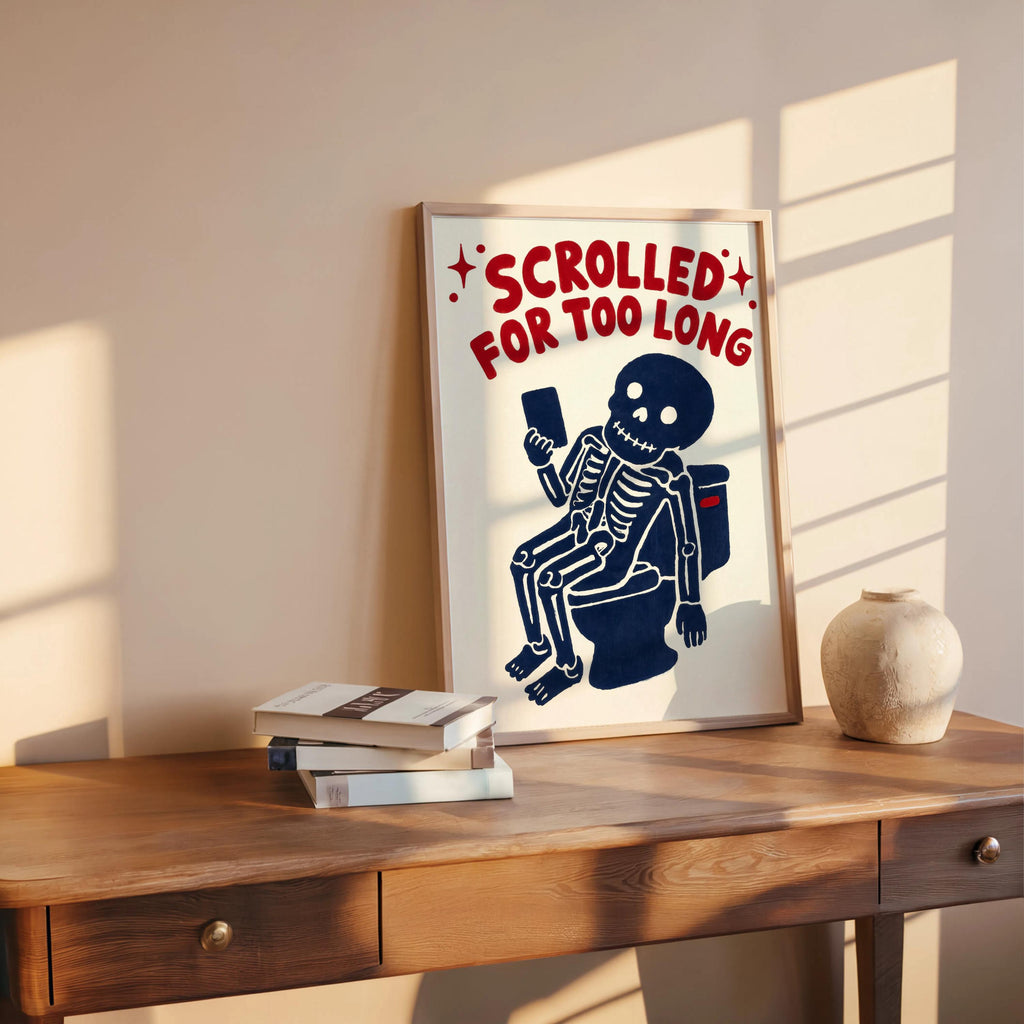 Funny skeleton bathroom art on a wooden shelf, framed quirky bathroom print with books and a small pottery vase