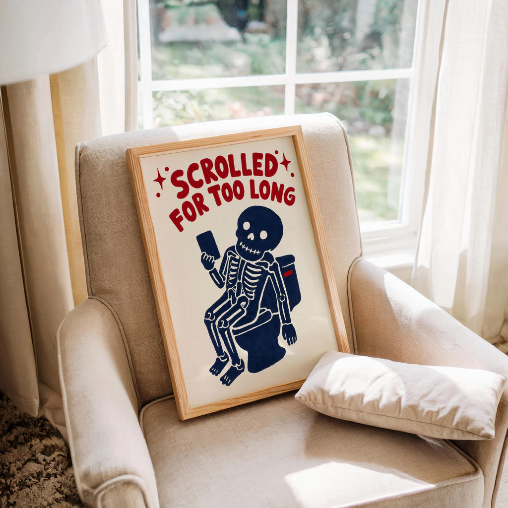 Funny skeleton bathroom art leaning on an armchair, vintage cream print with navy skeleton and red lettering
