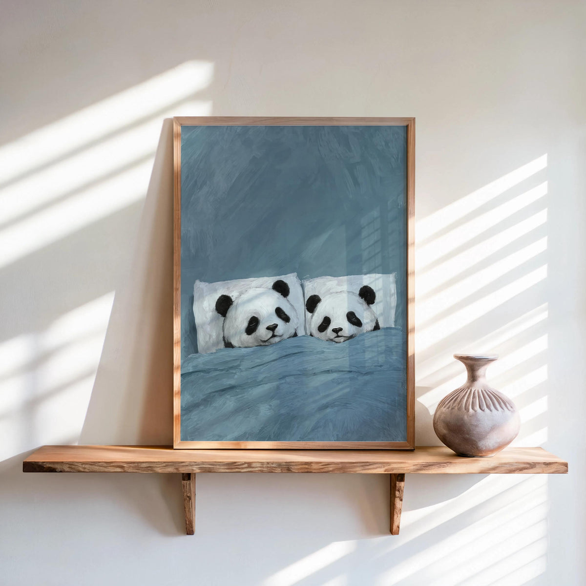 Muted blue sleeping panda wall art framed on shelf, diagonal sunbeams, cute panda art print for calm interiors
