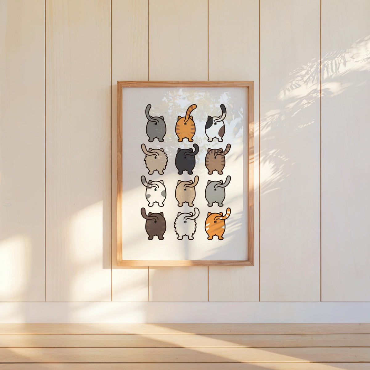 Framed print hanging on cream paneled wall, soft sunbeams illuminate twelve tails up, quirky cat wall art, cat lover gift idea