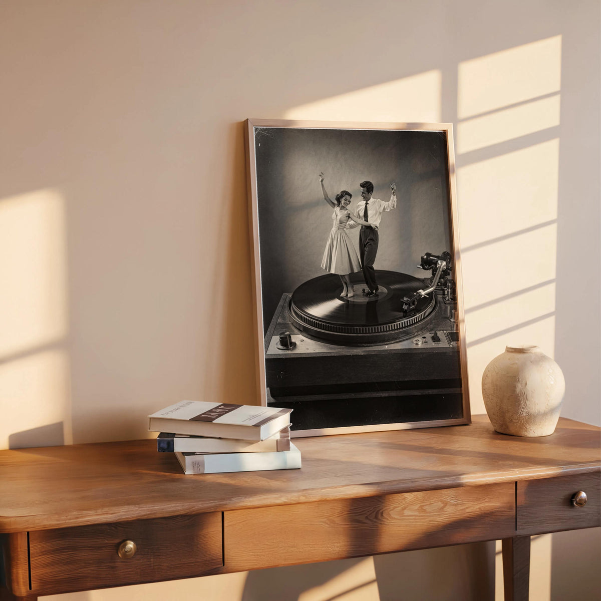 Leaned black-and-white record player wall art on wooden desk, books and ceramic sphere, warm sunlight cast