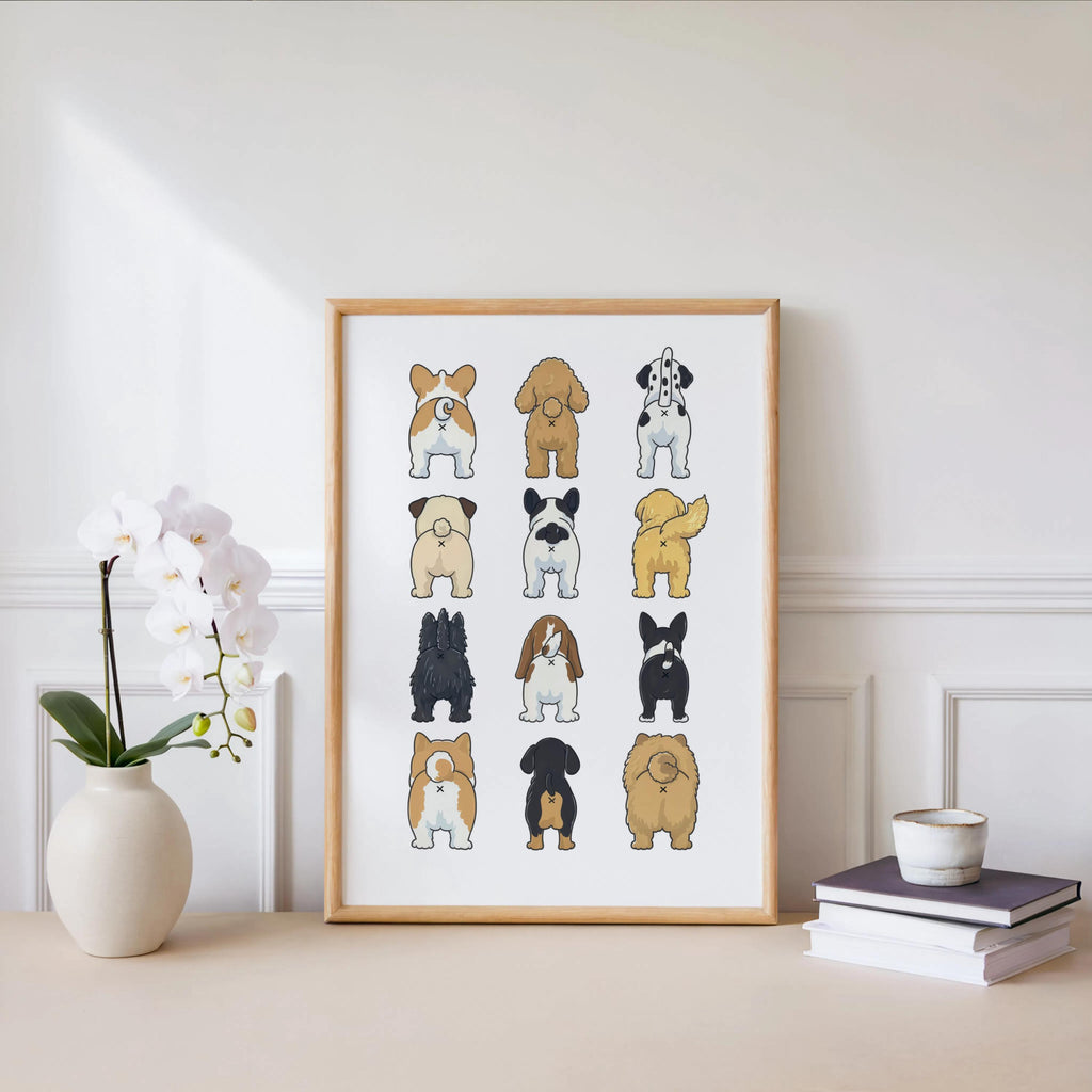 Framed funny dog butt bathroom art print beside a white orchid and stacked books, clean minimal decor