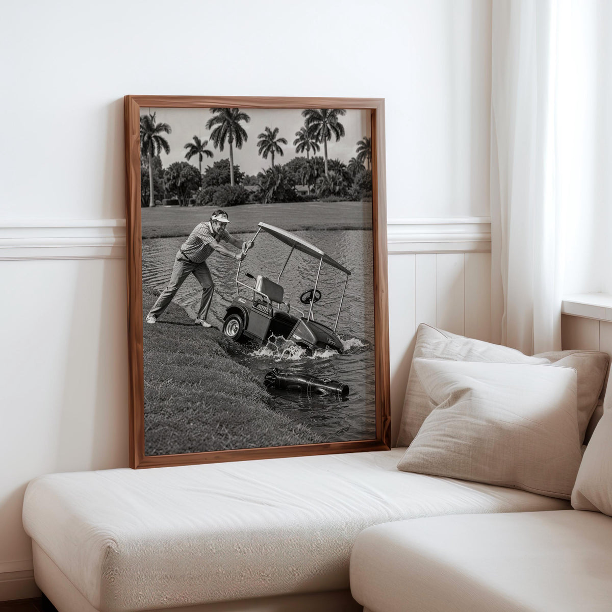 Angry golfer poster leaning against sofa chaise, framed mockup on neutral cushions, black and white.