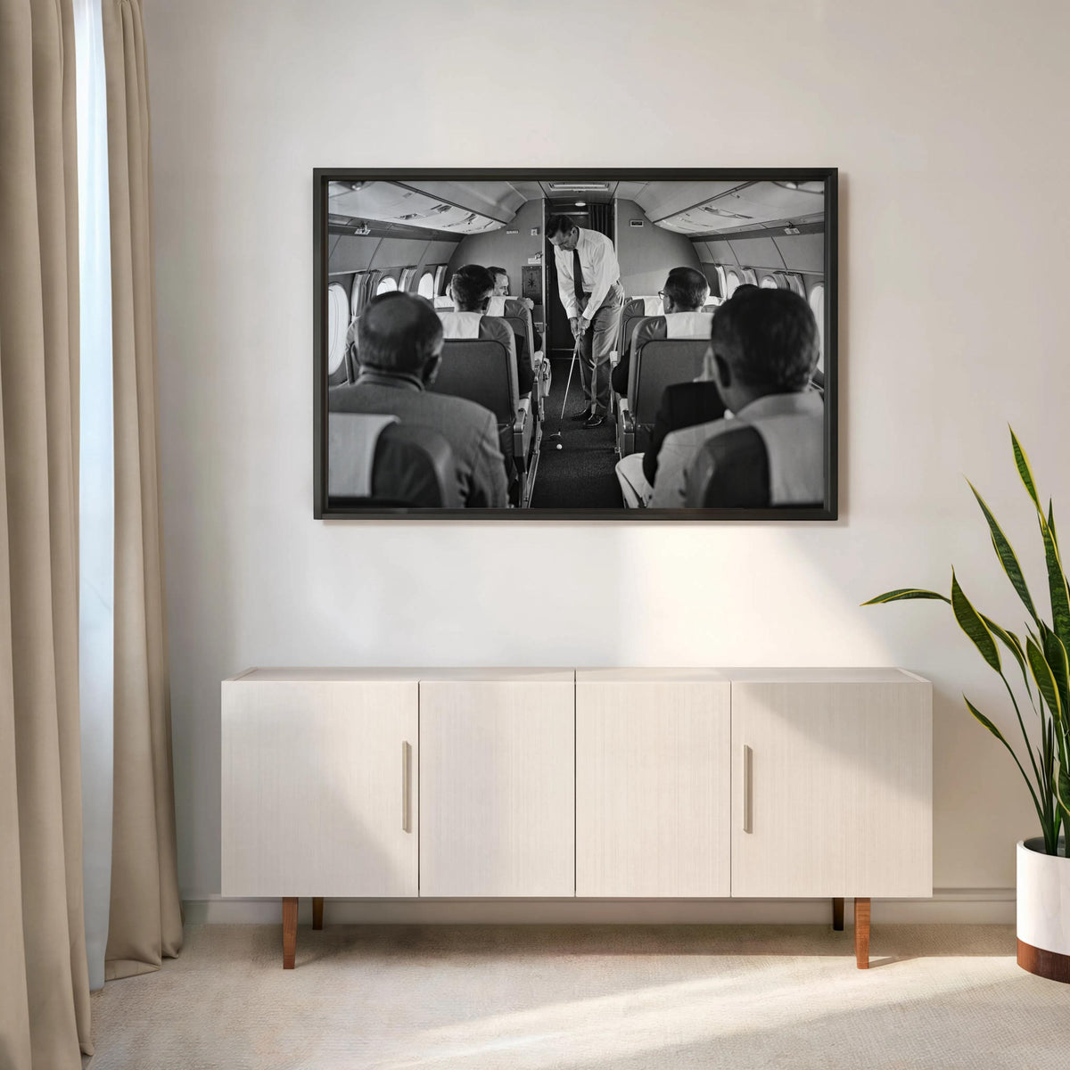 Black-framed print above a low cabinet, stark black and white golf art of a golfer swinging in an airplane cabin