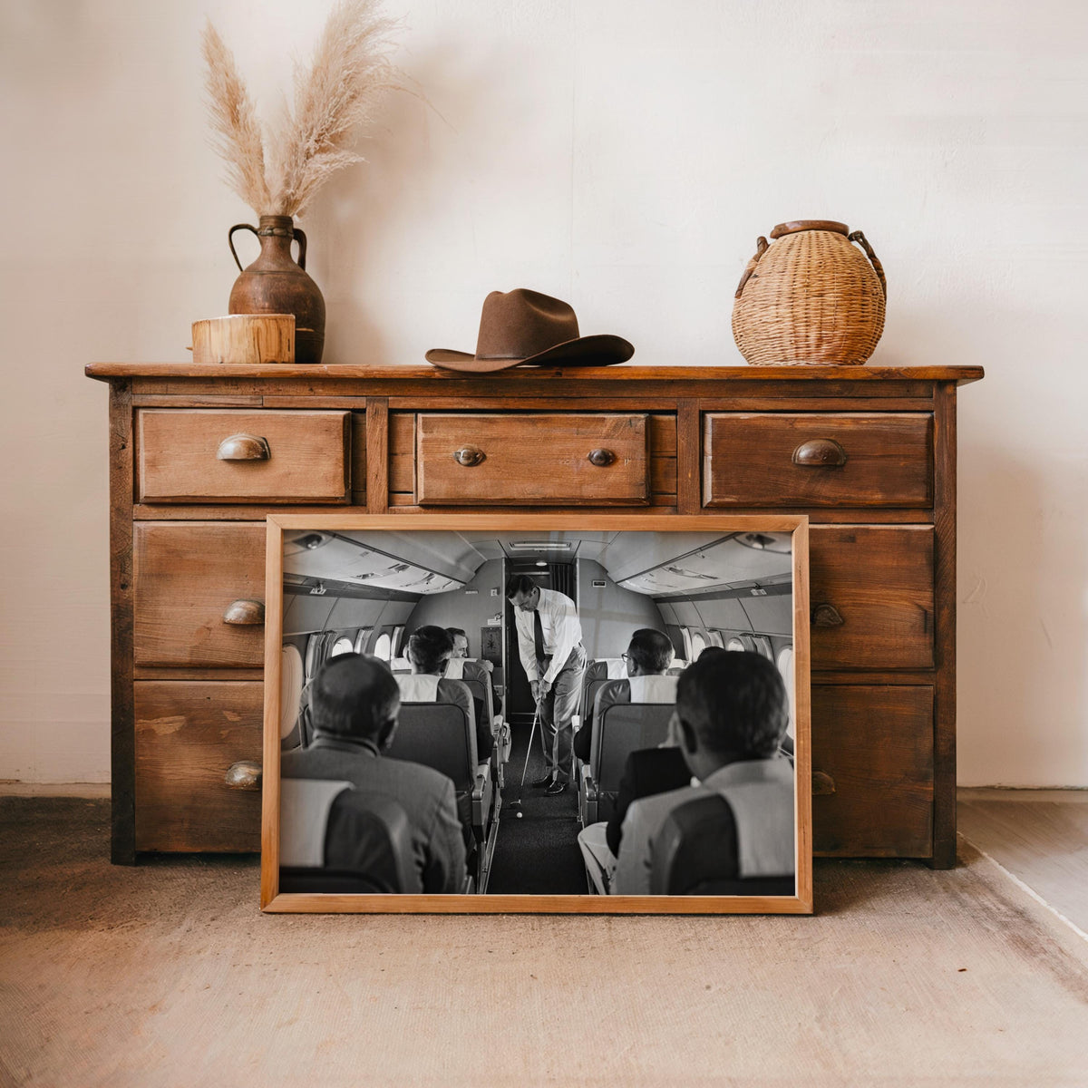 Wood-frame print leaning on rustic dresser with decor, monochrome airplane cabin golf scene, retro sports wall decor, funny golfer gift