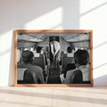 Sunlit wooden frame leaning on floor, monochrome golfer airplane print showing a surreal swing, funny golf wall art