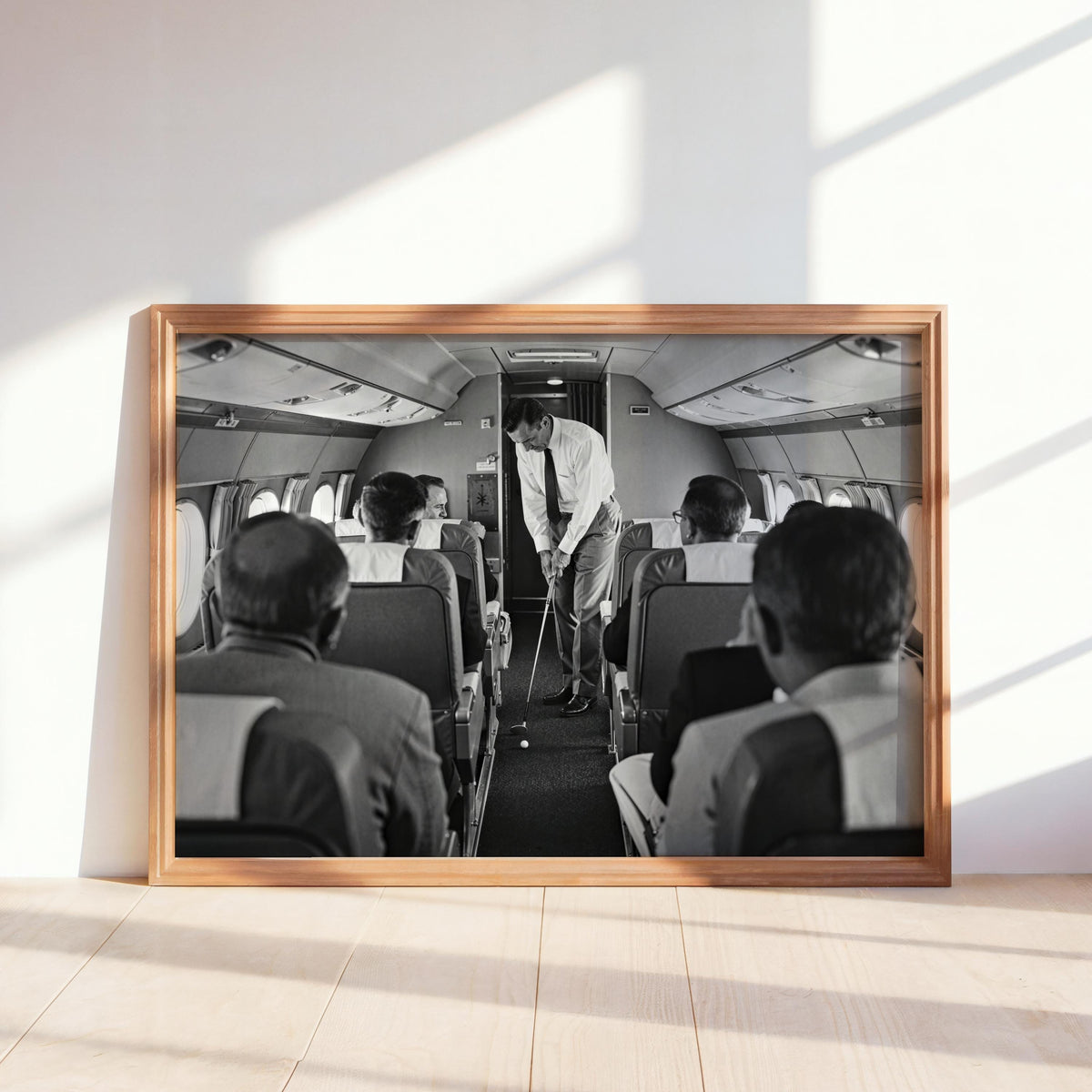 Sunlit wooden frame leaning on floor, monochrome golfer airplane print showing a surreal swing, funny golf wall art