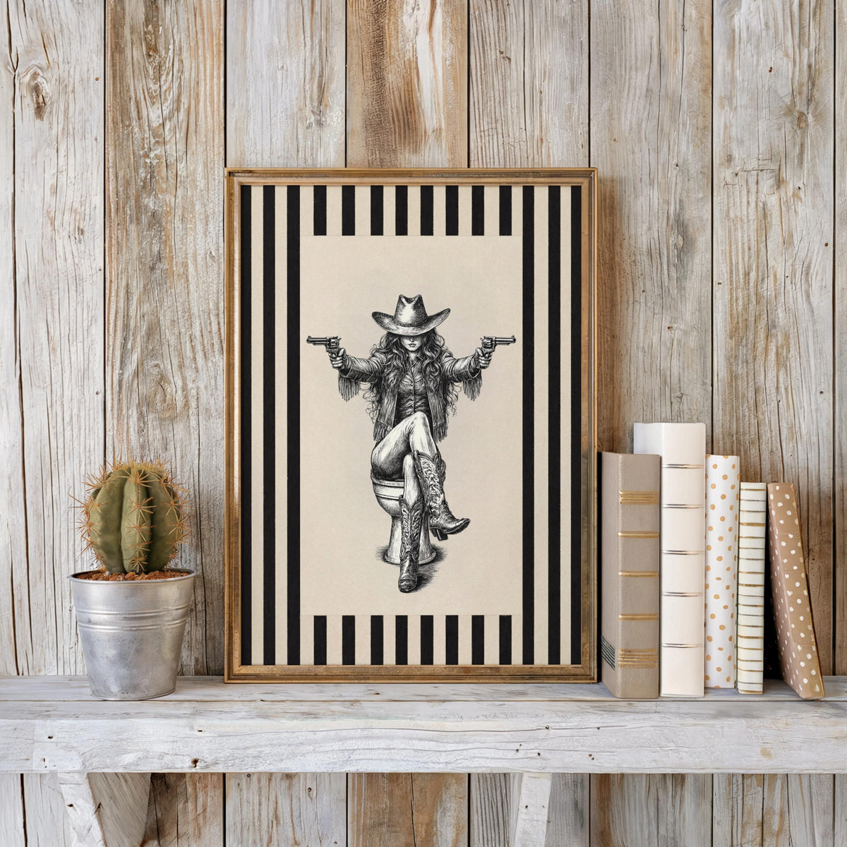 Framed cowgirl on toilet print leaning against weathered wood wall, cactus accent, western bathroom wall art