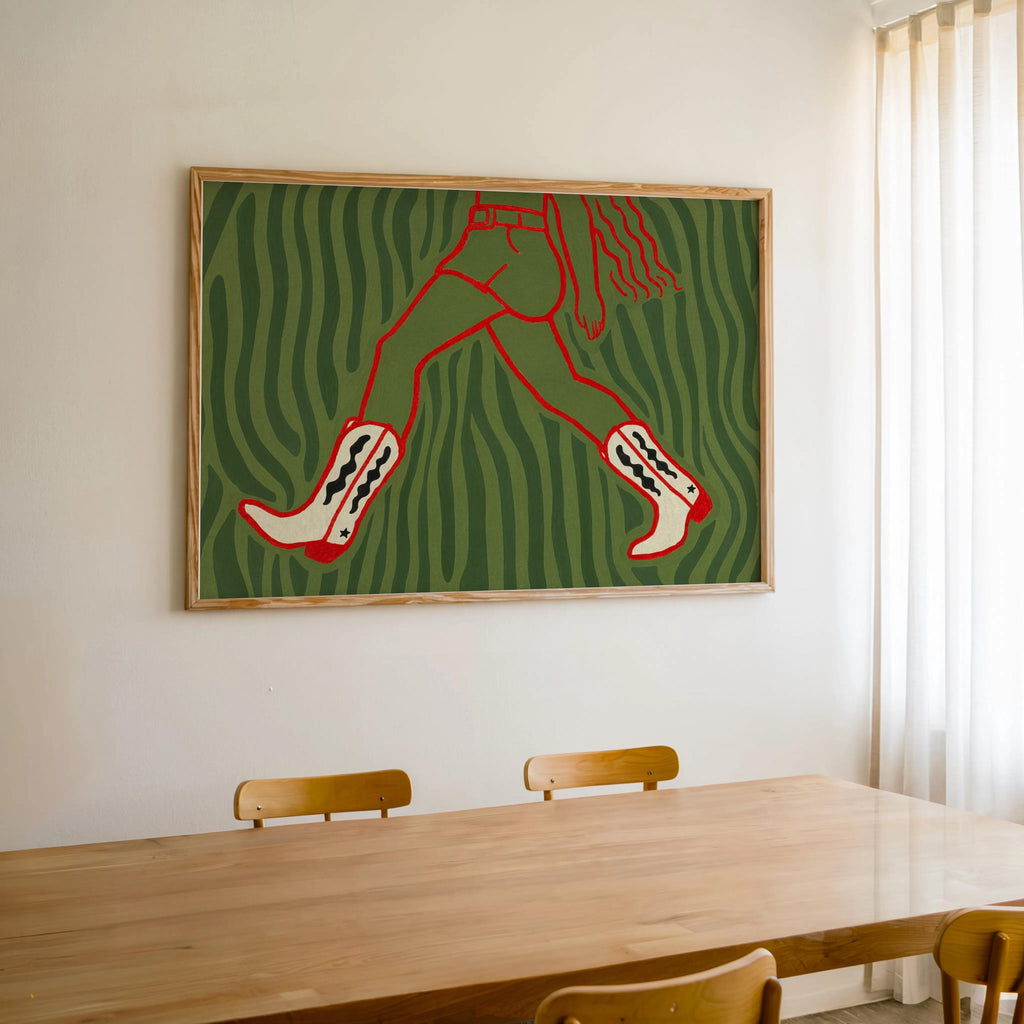 Green zebra-like cowgirl wall art print hung above table near sunlit window, western fashion print with red boots
