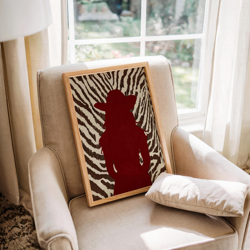 Armchair by window with framed cowgirl silhouette print, red and zebra tones suit cowgirl bedroom decor