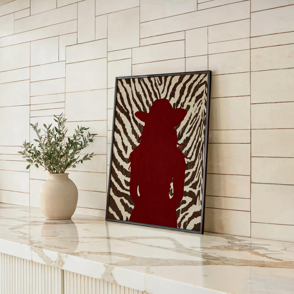 Leaning frame against shiplap, bold red cowgirl poster styled with plant, fashionable western print display