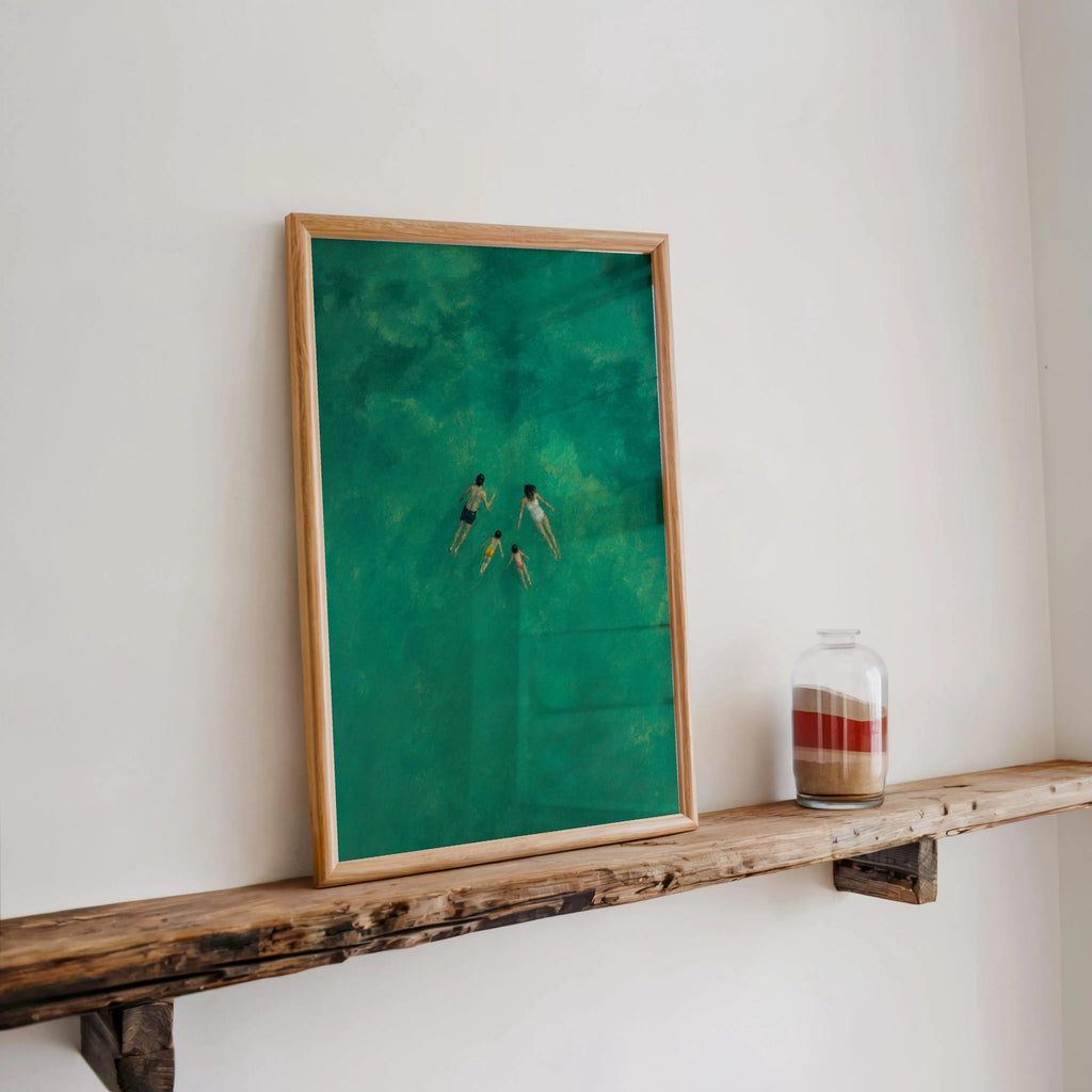 Aerial swimming art print propped on a narrow farmhouse shelf, luminous turquoise and emerald hues