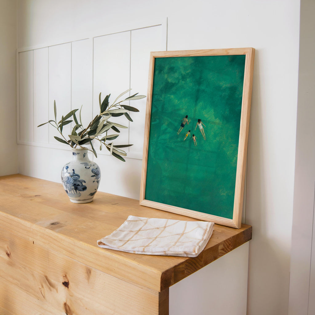 Coastal family wall decor on a wooden console, overhead view shows couple and kids in vibrant turquoise water