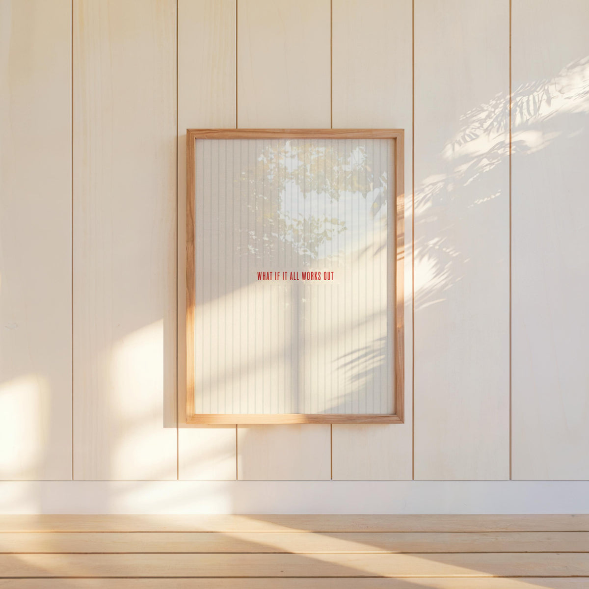 Hanging what if it all works out print on paneled wall, warm sunlight casting soft shadows