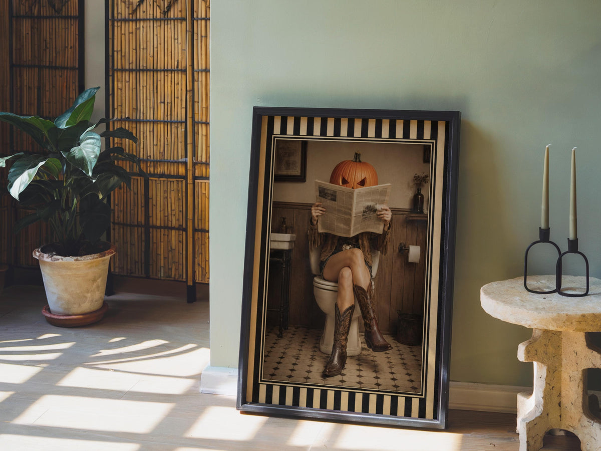Leaning sepia pumpkin head cowgirl art print beside a potted plant, western bathroom art staging idea