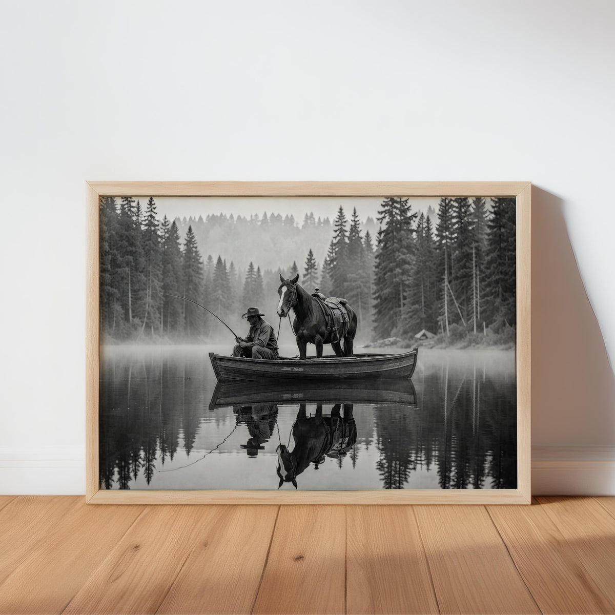 Wood-framed black and white cowboy fishing wall art leaning on floor, misty lake reflections