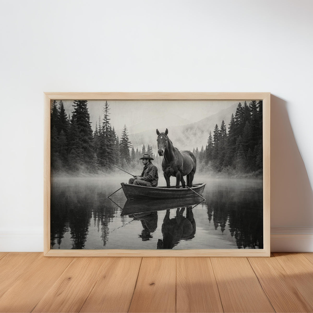 Framed black and white cowboy fishing wall art print leaning on hardwood floor, misty lake reflection
