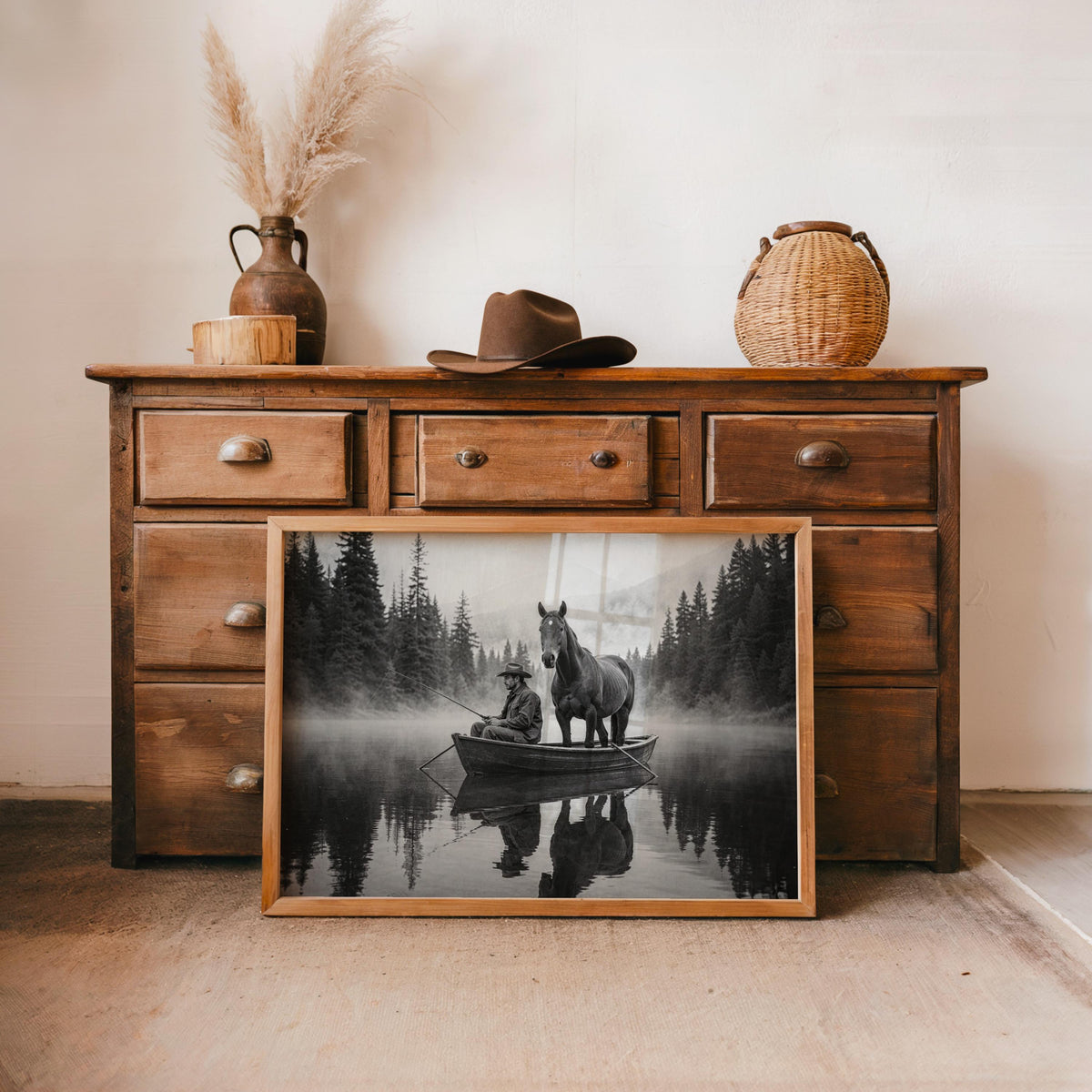 Two sizes of the cowboy fishing wall art print styled on a rustic wooden dresser, warm cabin accents