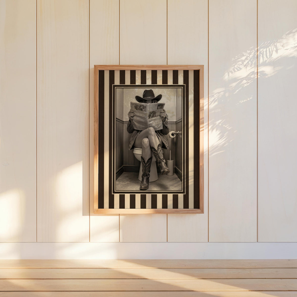 Bright paneled wall with hung vintage cowgirl print, bold striped western border and warm sunbeams, rustic western wall art, funny cowgirl bathroom wall art