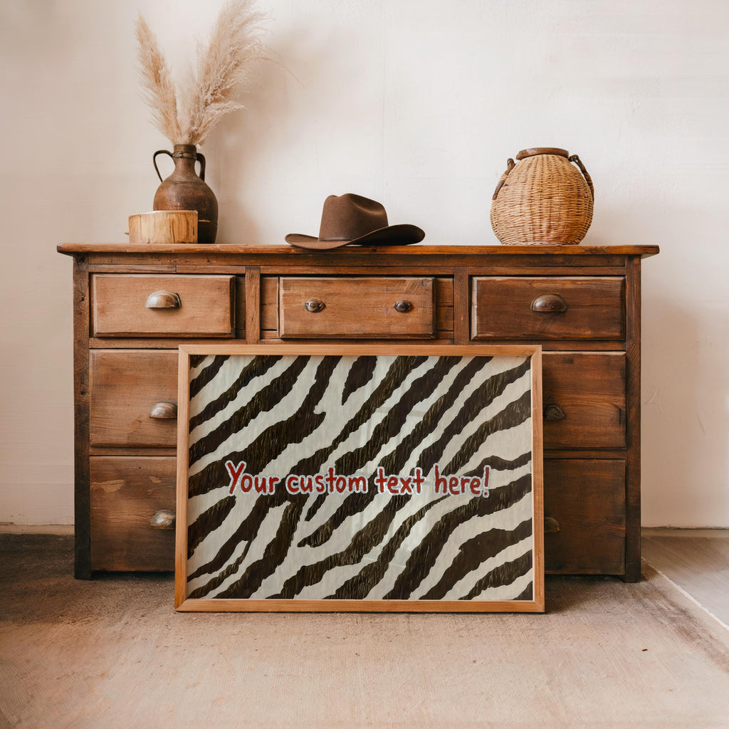 Framed personalized zebra print wall art propped against a wooden dresser, styled with wicker accents and dried pampas