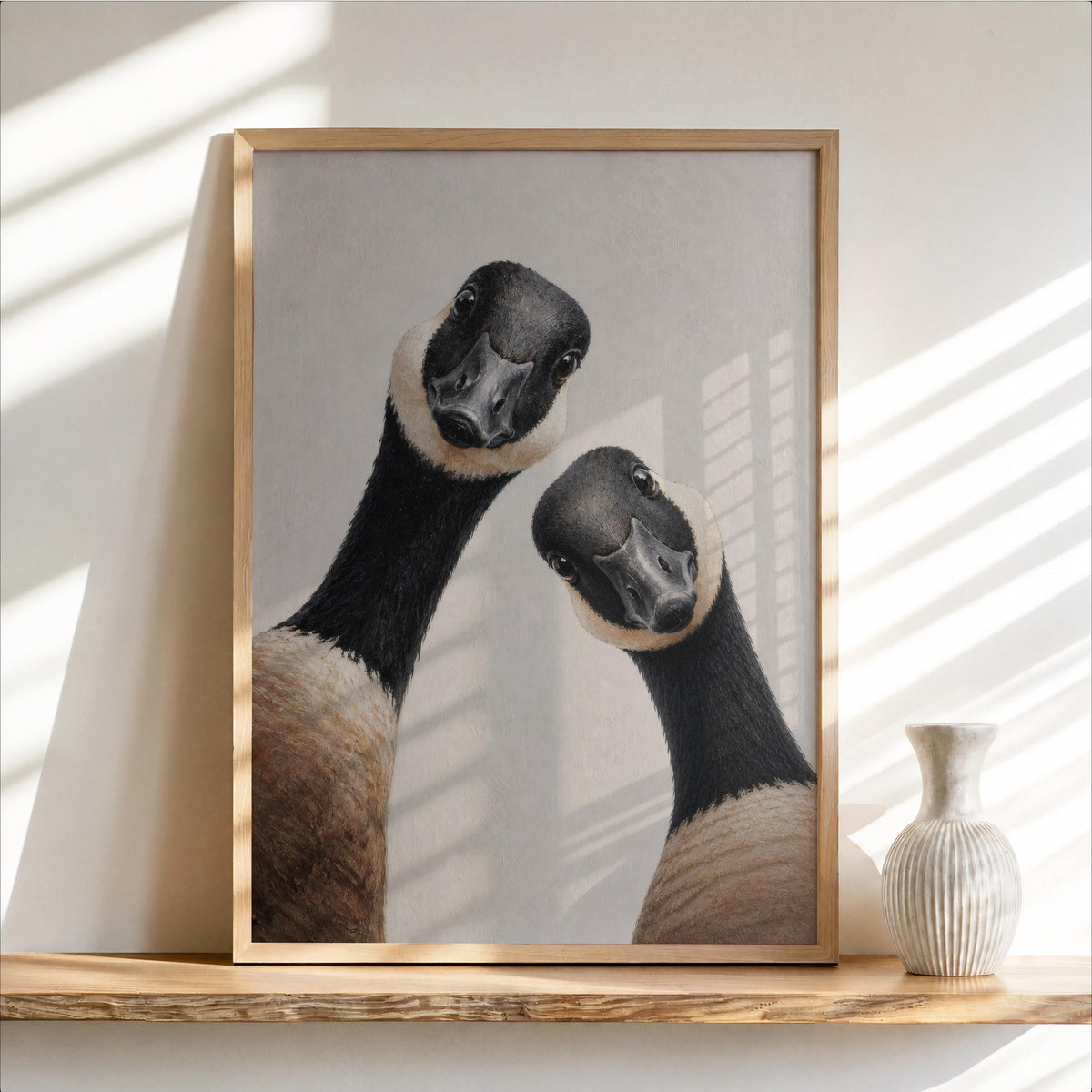 Framed Canadian geese wall art on a floating wood shelf, two curious geese, neutral tones
