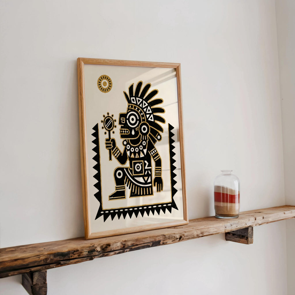 Black and gold wall art leaning on rustic shelf next to candle, bold Aztec design with feathered headdress