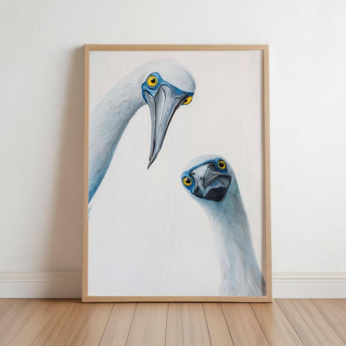 Light wood framed print leaning on oak floor, two curious blue-footed boobies, blue footed booby wall art print