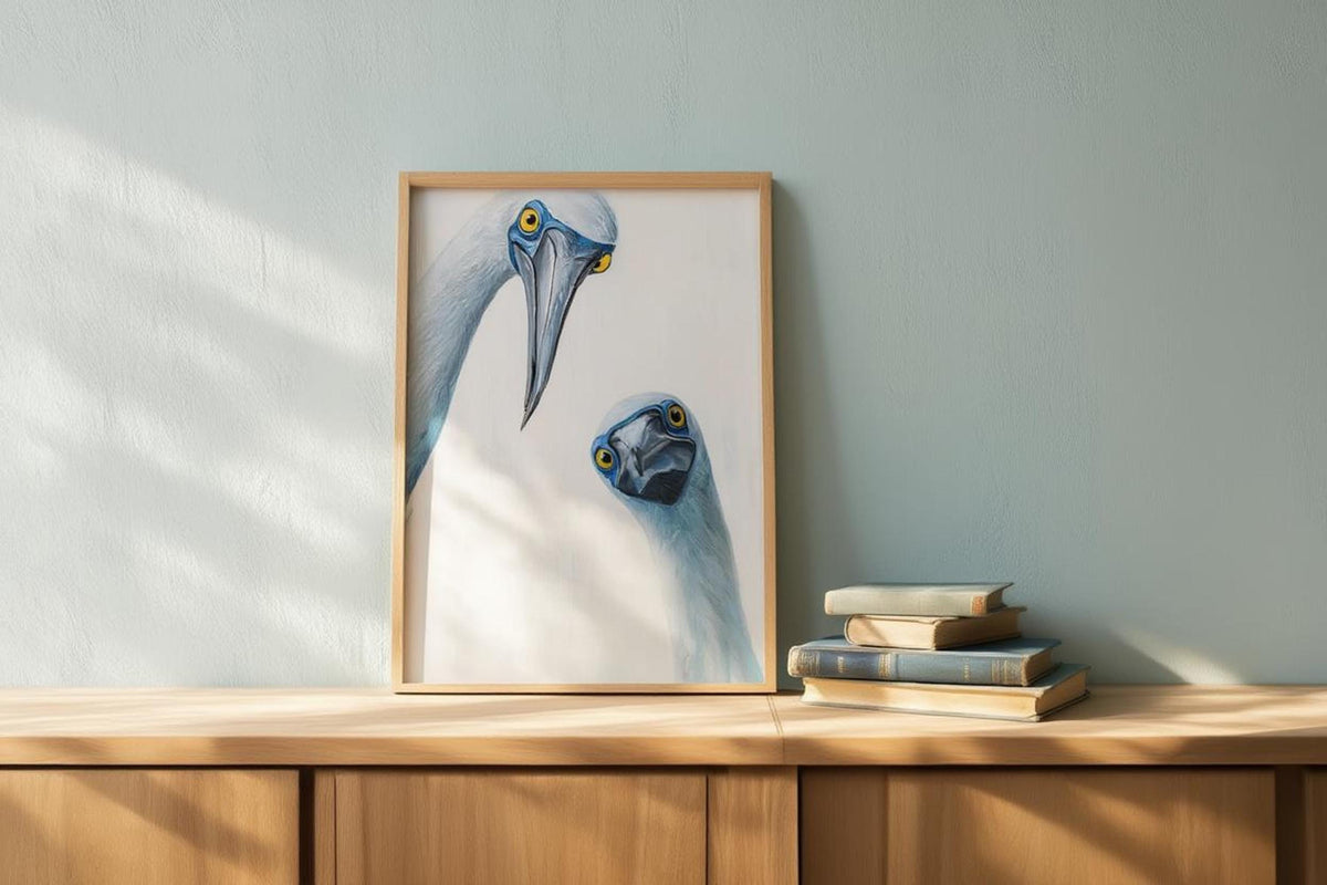 Frame on wooden surface near books with soft light on a pale green wall, quirky kitchen wall art feel, blue footed booby wall art print