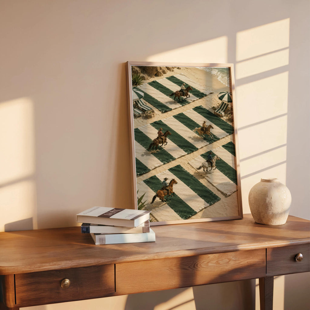 Coastal cowboy print propped on wooden desk with books and ceramic sphere, sunlight highlights green striped beach art