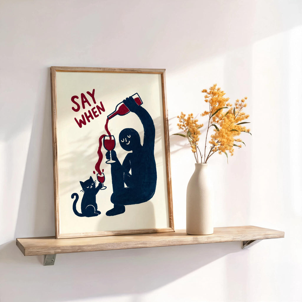Navy SAY WHEN print propped on floating shelf beside dried stems, warm light, wine lover wall art, funny cat wine wall art