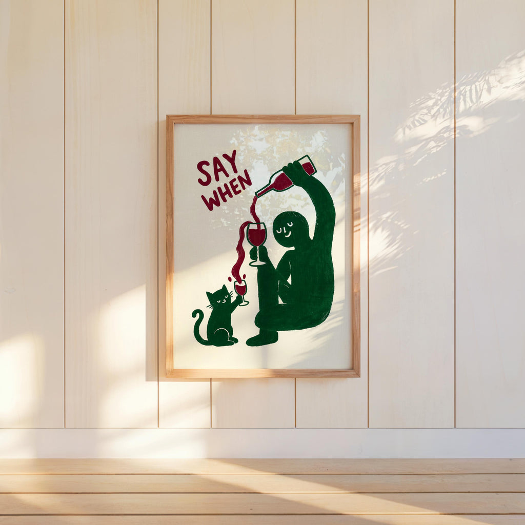 Wall-hung green SAY WHEN poster on white paneling, bright sun highlights and slight texture, quirky dining room decor, funny cat wine wall art