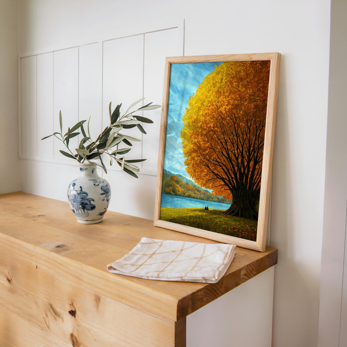 Autumn tree lake wall art displayed on a wooden console with a vase, golden tree landscape print for warm interiors