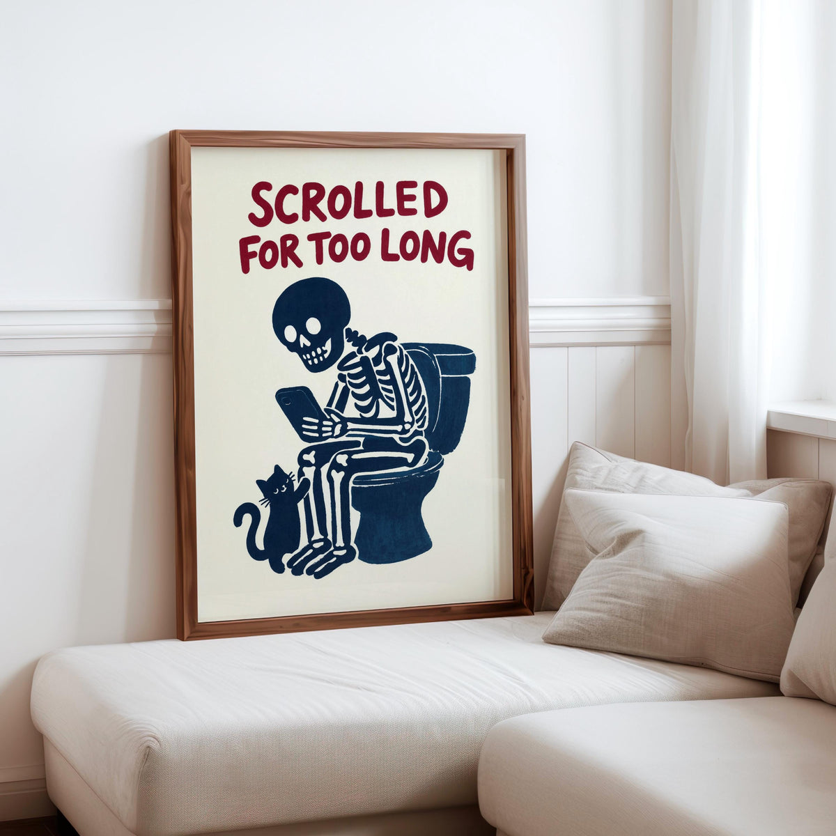 Framed skeleton bathroom decor propped on sofa, navy print, bold dark red typography reads Scrolled for Too Long