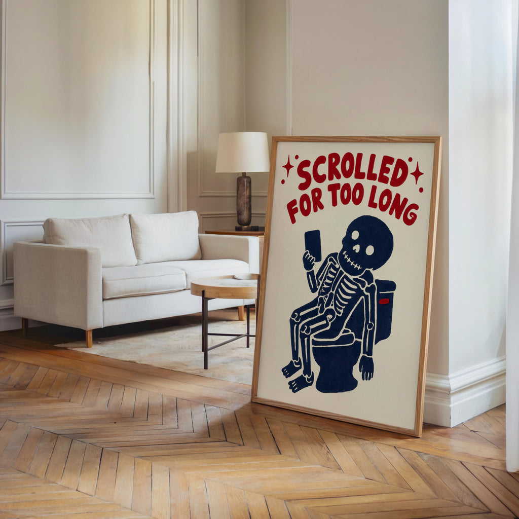 Funny skeleton bathroom art leaning in a minimalist living room, quirky bathroom print in a simple wood-toned frame