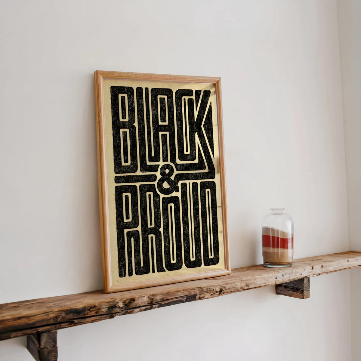 Framed Black and Proud wall art on a rustic live-edge shelf, distressed lettering, subtle Black pride poster energy