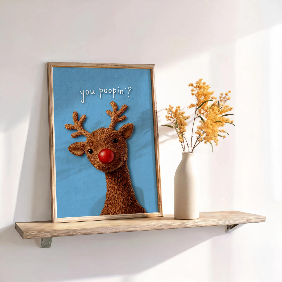 Styled shelf scene with blue Rudolph print and dried flowers, quirky Christmas wall decor ideal for guest bathroom