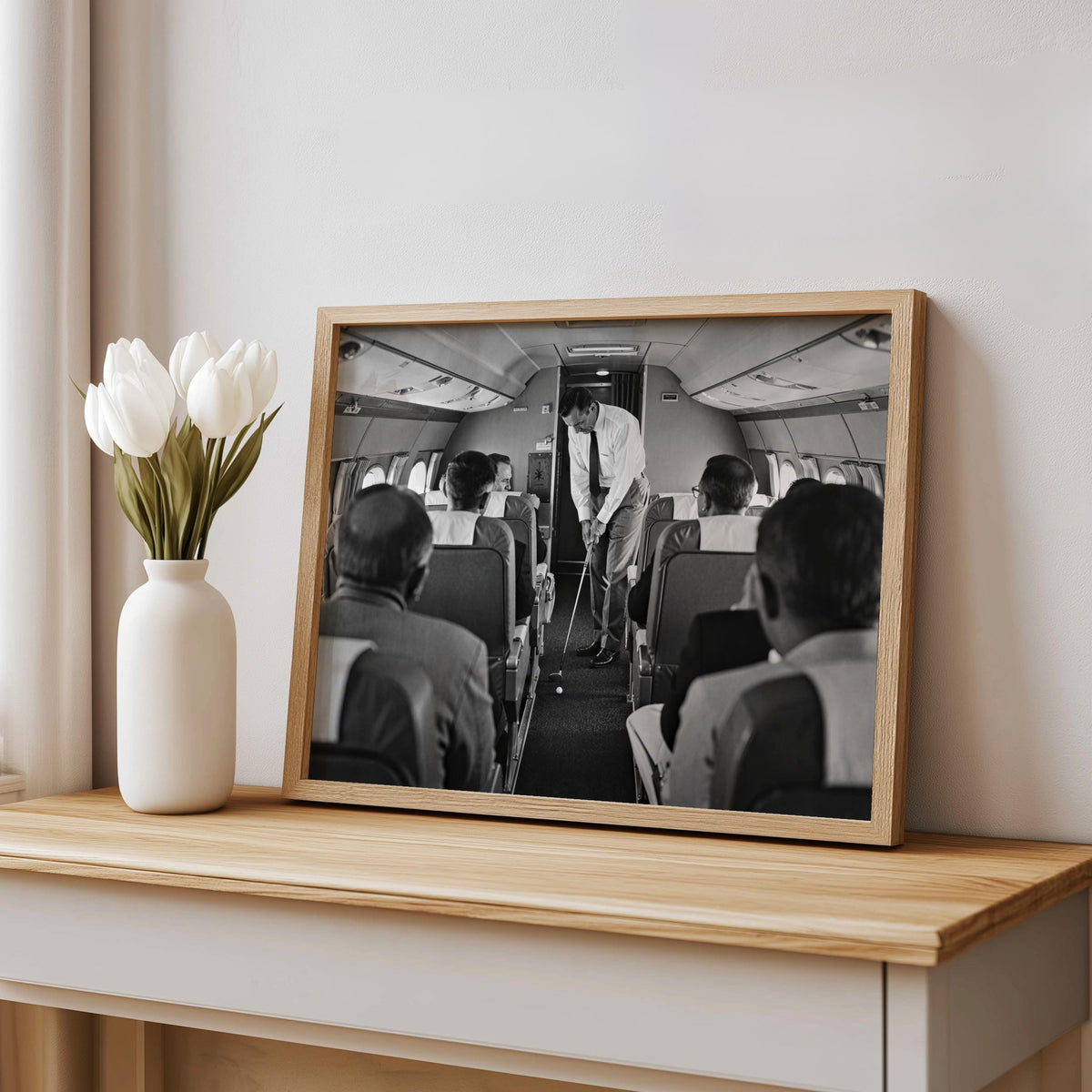 Wood frame print on shelf with tulips, black and white golf art showing a golfer in an airplane cabin