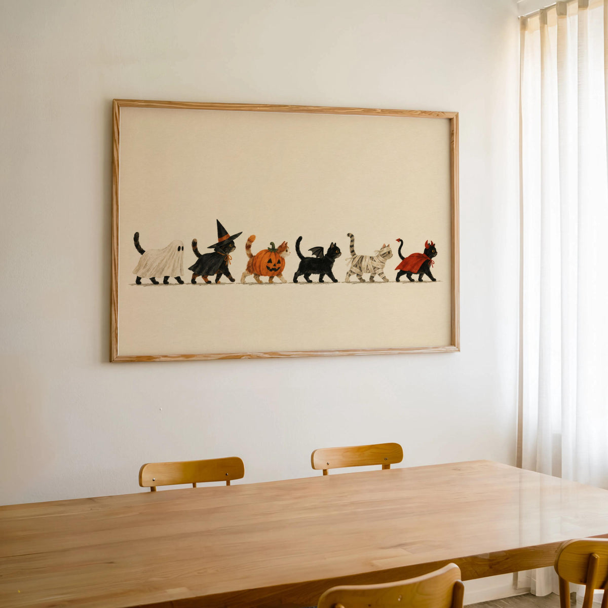 Framed Halloween cat wall art hung over wood table, warm cream backdrop, subtle spooky charm