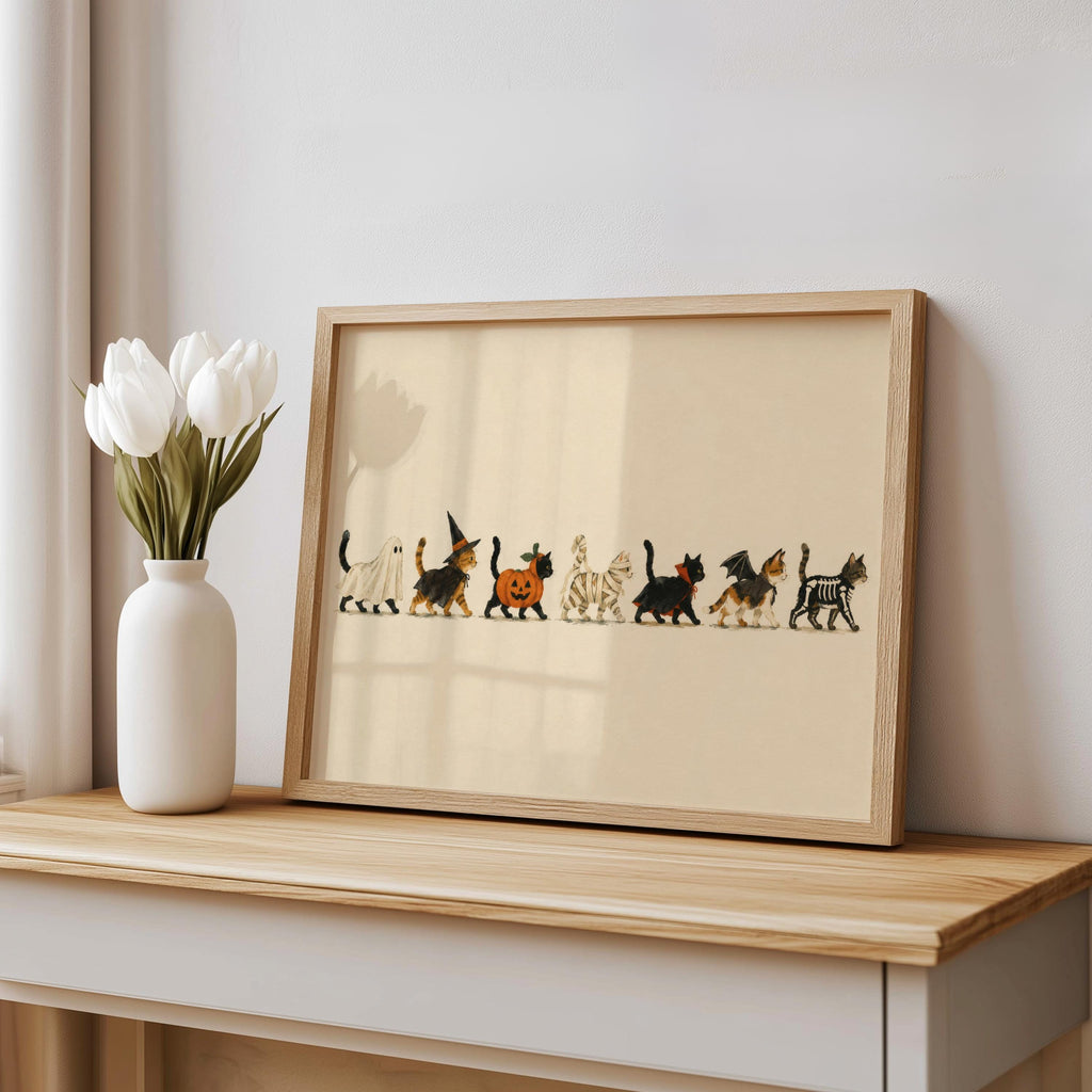 Framed Halloween cat wall art on shelf beside white tulips, storybook Halloween print, soft cream tones.
