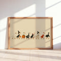 Sunlit wood-framed Halloween duck print leaning against wall, cream background, ducks in costumes