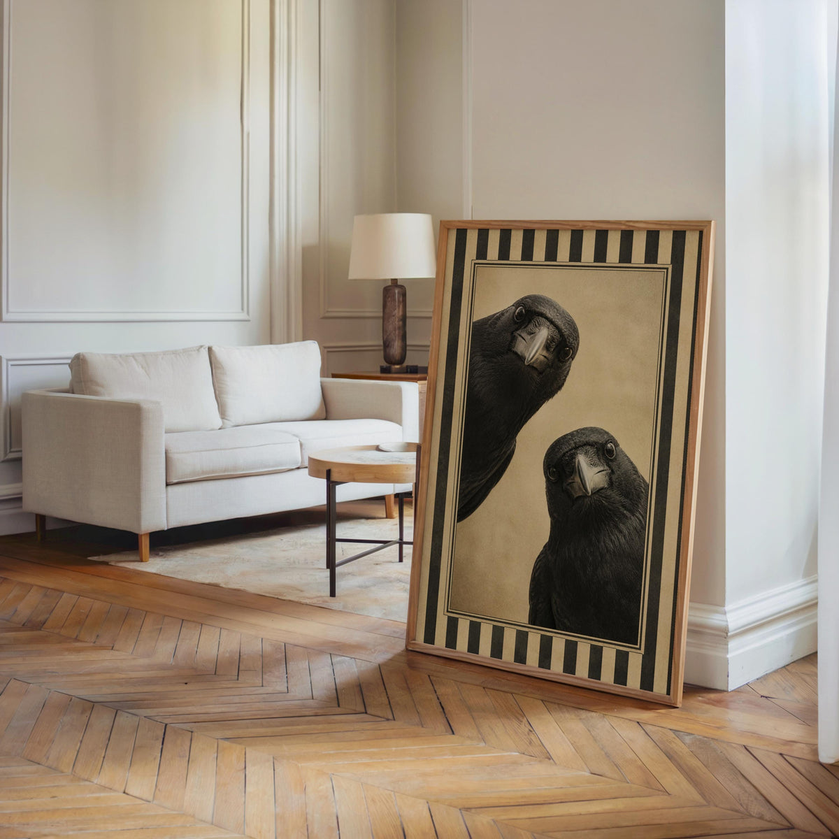 Two crow art print propped in an airy living room corner, hardwood floor and sofa, dark academia wall art energy