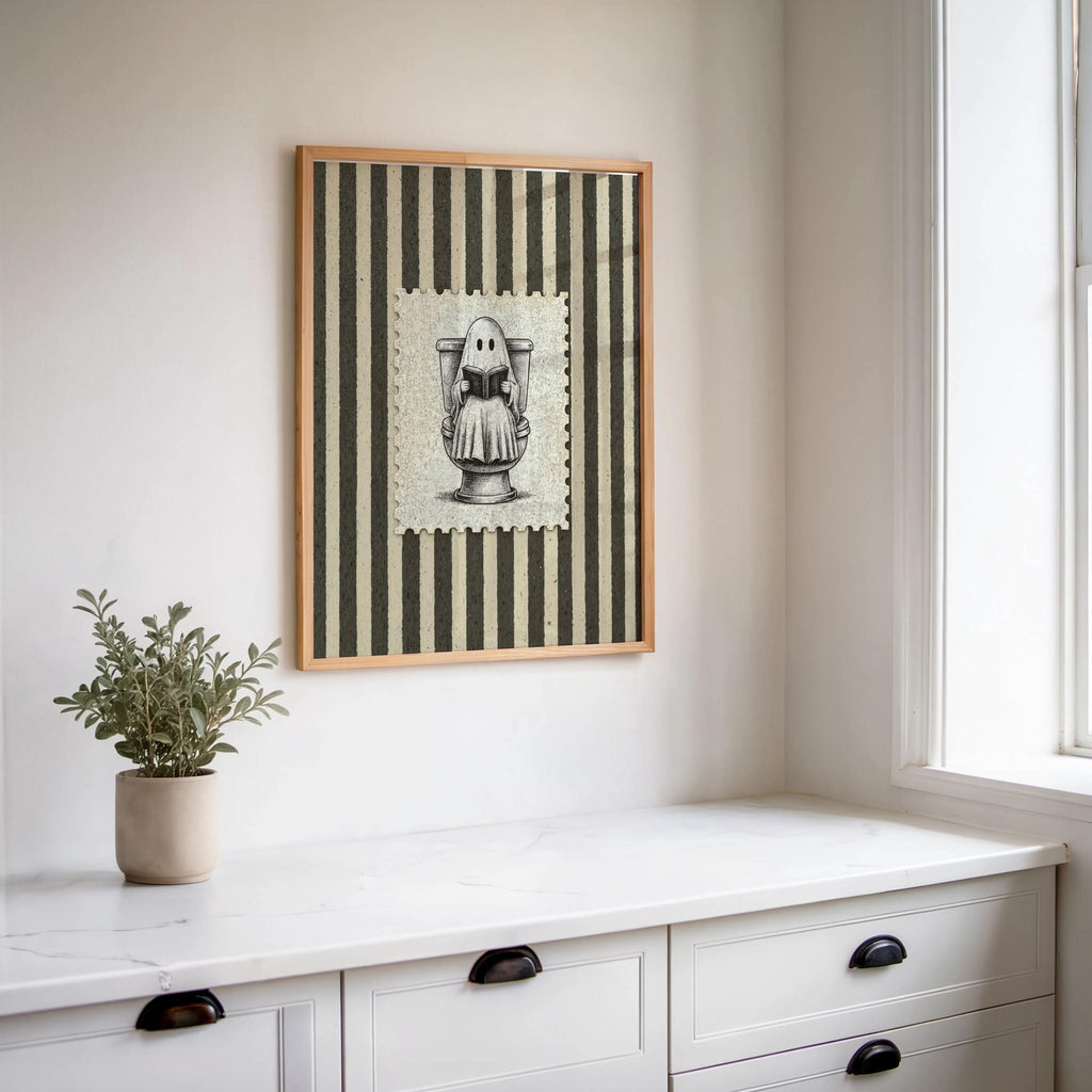 Small framed antique Halloween illustration hung above a white dresser with a potted plant, ghost bathroom art, funny bathroom wall art