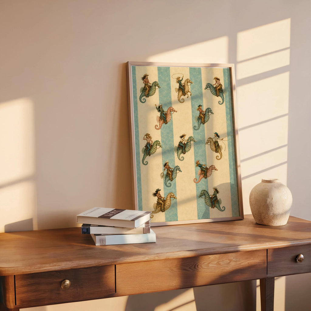 Coastal cowgirl print styled on a wood desk with books and pottery, warm morning light highlights seahorse design