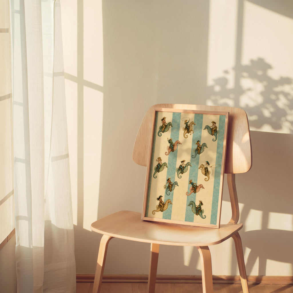 Sunlit mid-century chair holds the coastal cowgirl art print, lamp casting shadows on vintage seahorse stripes
