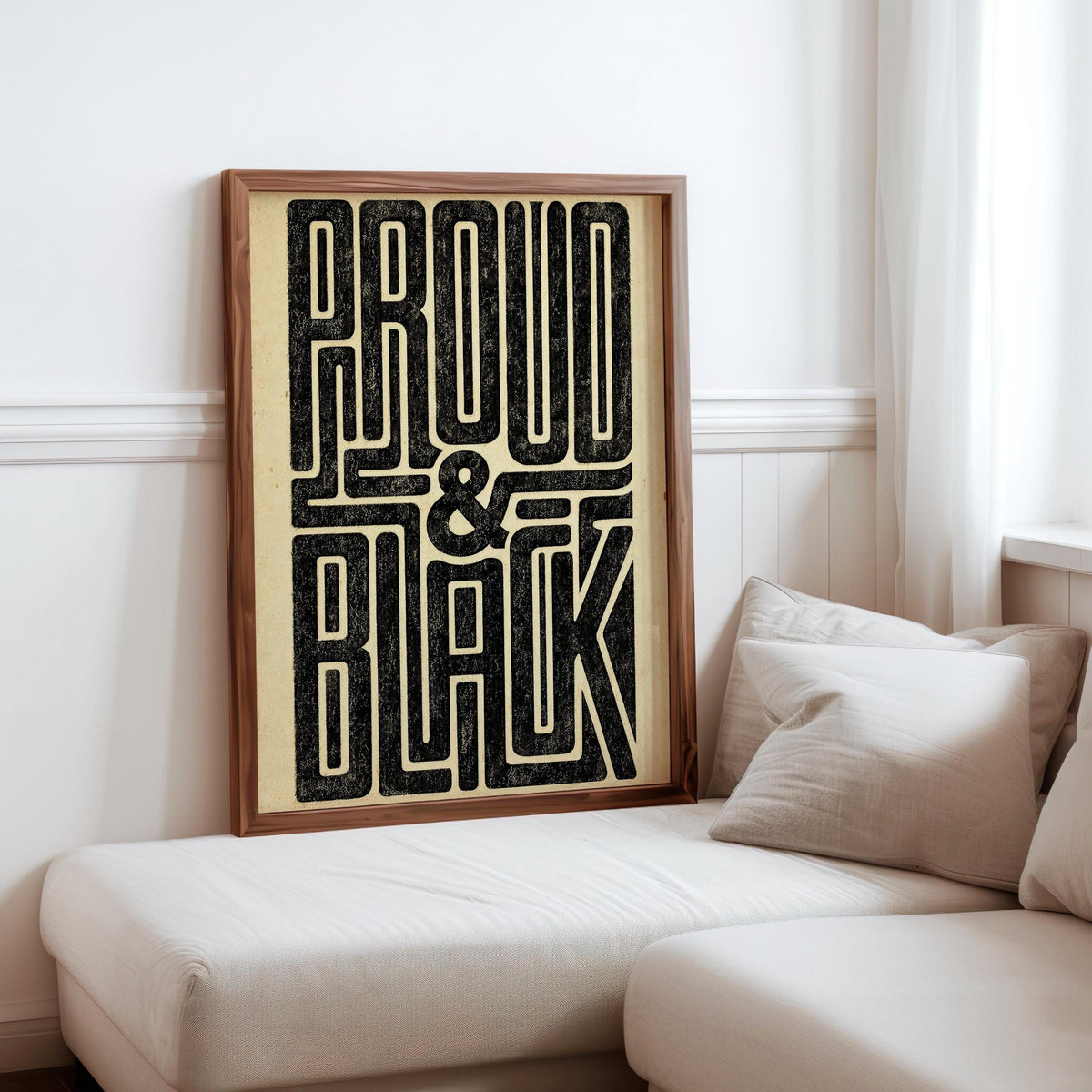 Neutral sitting nook with cushion and framed Proud and Black poster on low bench, bold statement wall art