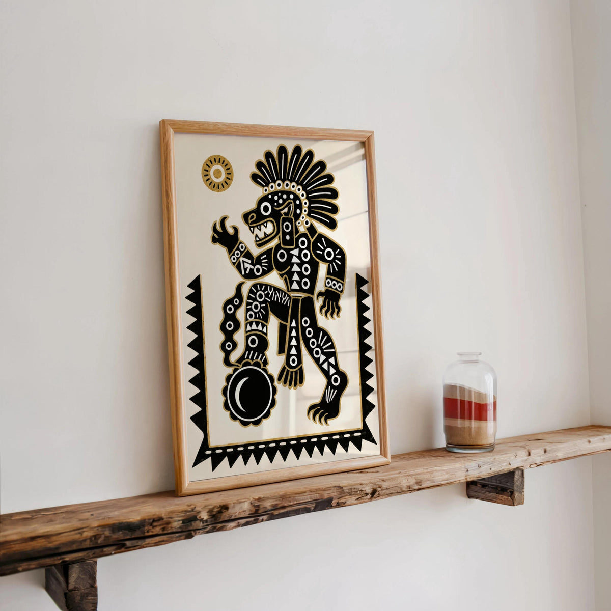 Tezcatlipoca art print on a rustic wooden ledge against white wall, geometric borders and gold motif, Latin American wall art