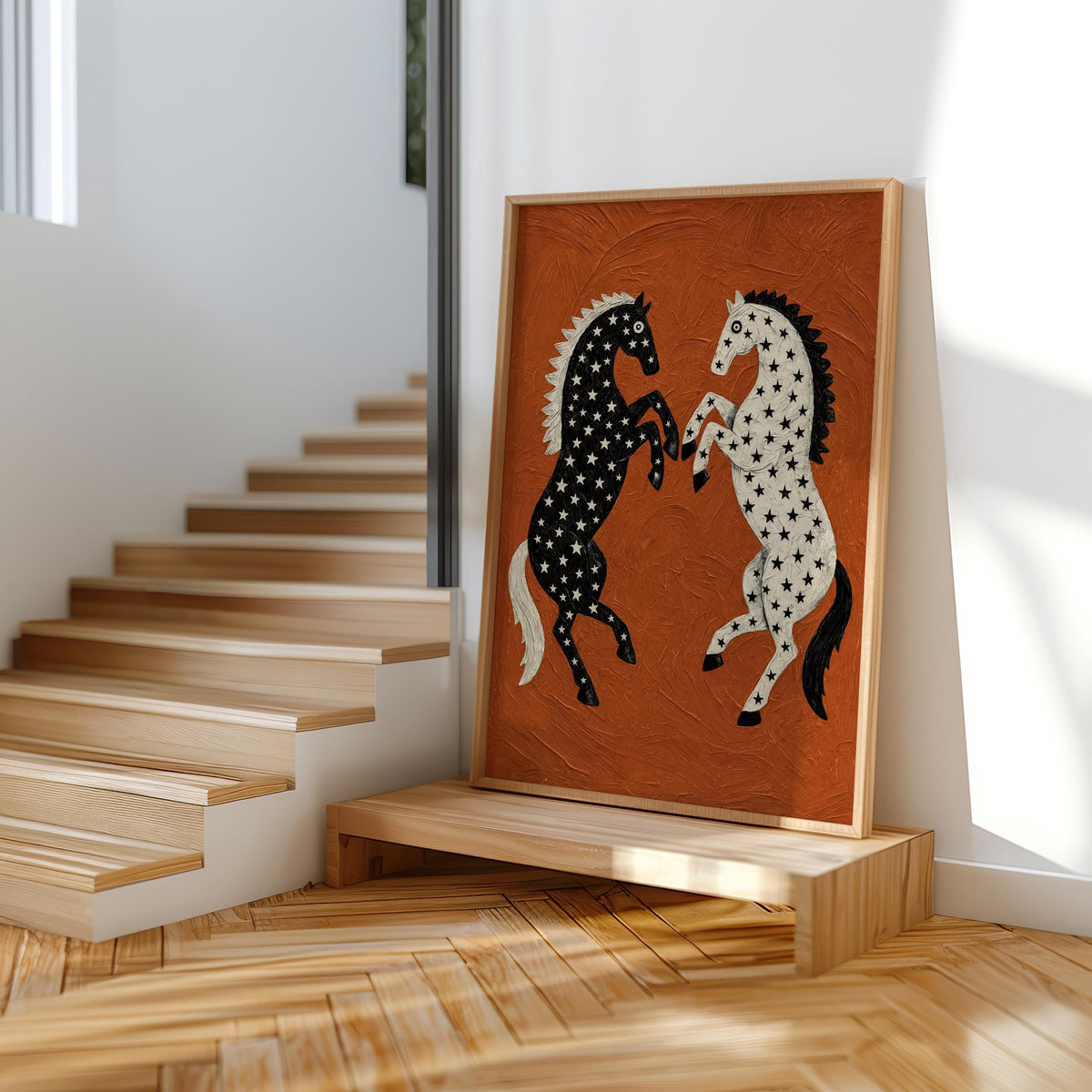 Framed folk art horse print resting on a low stair display, bright daylight, rustic wood tones complementing the black and white rearing horses